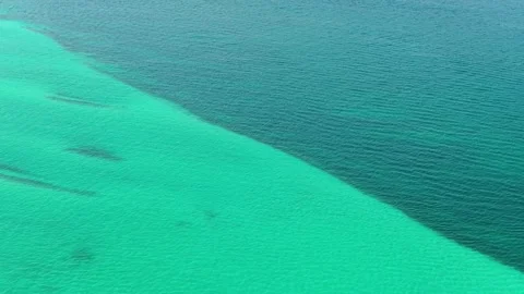 Aerial view of a striking contrast between shallow turquoise and deeper blue Stock Footage 346699785