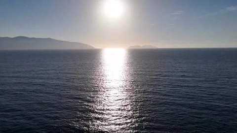 Aerial view of sun reflecting on calm sea waters with distant islands Stock Footage 336315437
