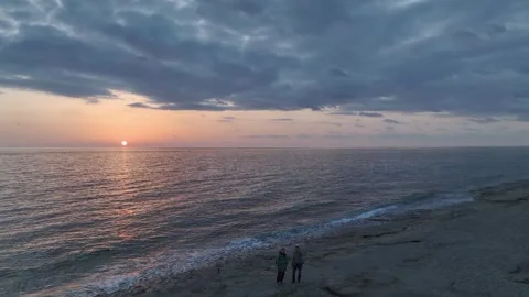 Aerial View: The sun sets over the ocean, painting the horizon in fiery colors Stock Footage 296077230