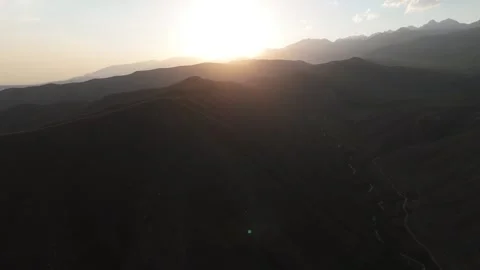 Aerial view of the sun setting behind mountain ridges, Kyrgyzstan Stock Footage 347240123