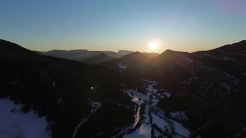 Aerial view of the sun setting over a snow covered valley Stock Footage 328615502