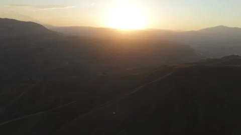 Aerial view of the sun setting over mountain ridges, Gulcha, Kyrgyzstan Stock Footage 347241961