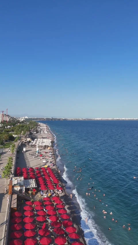Aerial view of sunbathing people at a beach with colorful umbrellas by sea Stock Footage 344358990