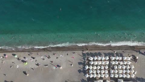 Aerial view of sunbathing people at the beach with umbrellas by turquoise sea Stock Footage 346561292