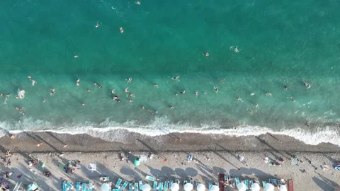 Aerial view of sunbathing people at the beach with umbrellas by turquoise sea Stock Footage 346561435
