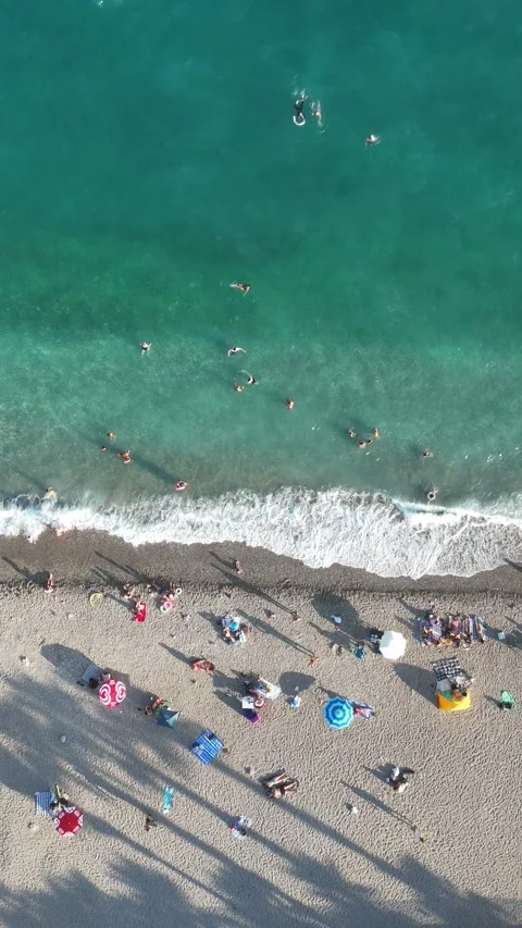 Aerial view of sunbathing people at the beach with colorful beach umbrellas Stock Footage 346610399