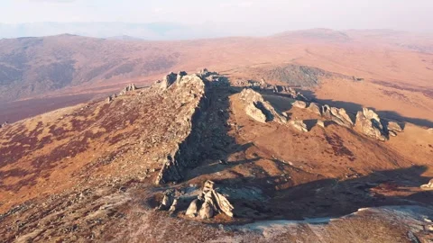 Aerial view sunlight gently illuminating rocky mountain ridge at sunset Stock Footage 298182133