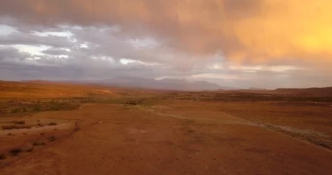 Aerial view of sunset and rainbow over a desert landscape and mountains Stock Footage 99479645