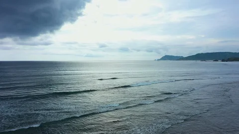 Aerial view of a sunset behind dark grey clouds. Flying slowly above dark ocean Stock Footage 129280590