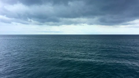Aerial view of a sunset behind dark grey clouds. Flying slowly above dark ocean Stock Footage 129280756