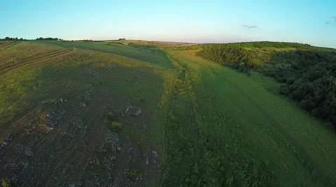 Aerial View, Sunset Flight over a green grassy hills. Video stock 65036986
