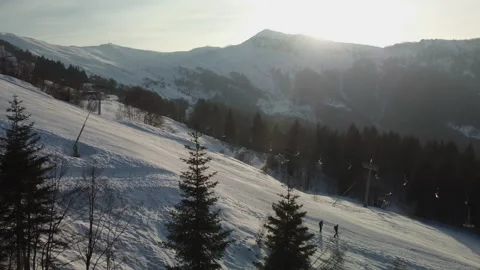 An aerial view at sunset light a snowy mountain and two happy hikers walking. 库存影片 152988909
