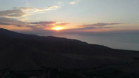 Aerial view of sunset over Issyk-Kul lake and mountain silhouettes, Kyrgyzstan Видео 347239885