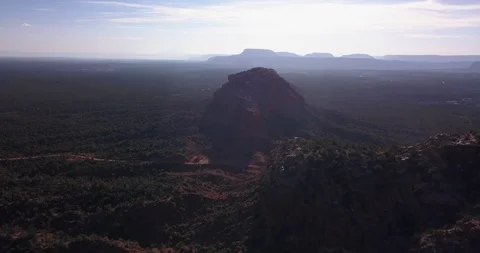 Aerial view of sunset over red mountain bluffs in a cedar forest Stock Footage 99562524