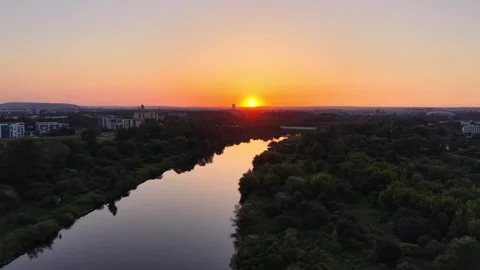 Aerial view of sunset over a river reflecting vibrant colors, with lush greenery Stockbeeldmateriaal 341472949