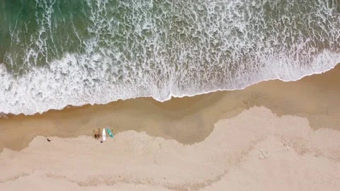 Aerial view of surf waves brushing and breaking on the white sandy seashore on a Stock Footage 154534724