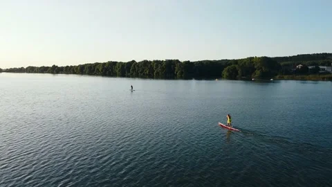 Aerial view of a surfer floating on a board along a river wave at sunset Stock Footage 139199767