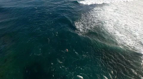 Aerial view of a surfer paddling out to the lineup through the channel Stock Footage