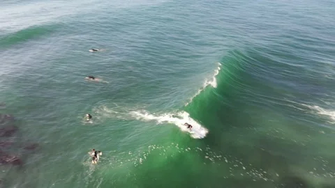 Aerial View of a Surfer Riding Waves Along the Coastline Stock Footage 150724857