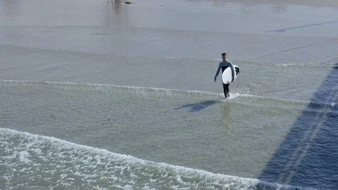 Aerial View Of Surfer Walking Into Waves, Along Pier, For Surf Session Stock Footage 98315993