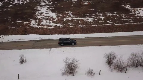 Aerial view of an SUV driving down a snowy road Stock Footage 89455616