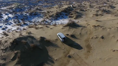 Aerial view of suv moving in the snow-capped desert in winter. Western Video stock 80244021