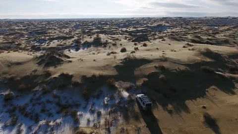 Aerial view of suv moving through the snow-covered desert in winter. Western Stock Footage 80987140