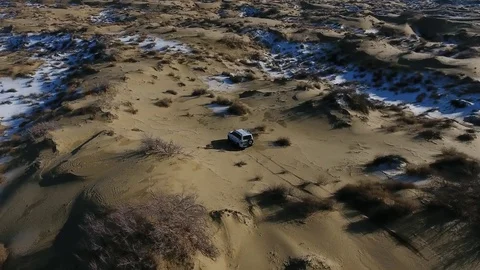 Aerial view of suv moving through the snow-covered desert in winter. Western Stock Footage 80987438