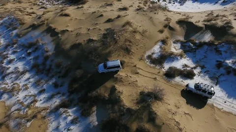 Aerial view of suv moving through the snow-covered desert in winter. Western Stock Footage 93579774