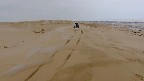 Aerial view of suv moving through the snow-covered desert in winter. Western Stock Footage 93689426