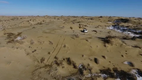 Aerial view of suv standing in the snow-capped desert in winter. Western Stock Footage 80243940