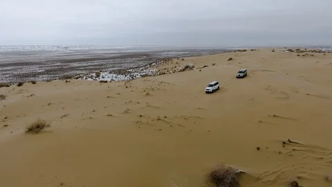 Aerial view of suvs moving through the snow-covered desert in winter. Western Stock Footage 93688044