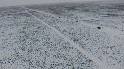 Aerial view of suvs moving through the snow-covered desert in winter. Western Stock Footage 93688901