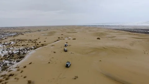 Aerial view of suvs moving through the snow-covered desert in winter. Western Stock Footage 93689122