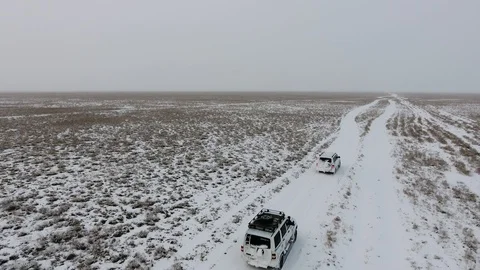 Aerial view of suvs moving through the snow-covered desert in winter. Western Stock Footage 93689199