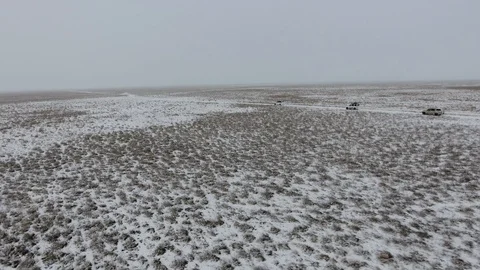 Aerial view of suvs moving through the snow-covered desert in winter. Western Stock Footage 93689345