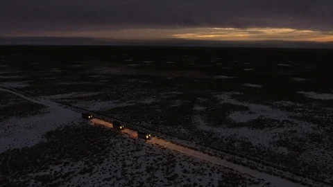 Aerial view of suvs moving through the snow-covered desert in winter at night Stock Footage 93832965