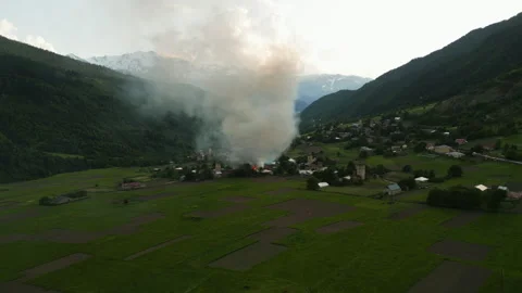 Aerial view of Svan tower on fire in Mestia valley, Svaneti mountains. Smoke Stock Footage 309199098