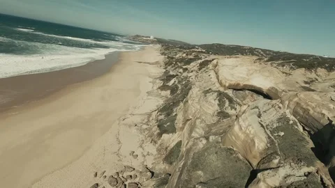 Aerial view sweeps over sandy beach meeting ocean waves Stock Footage 341822126