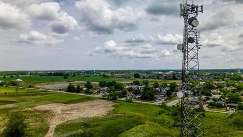 Aerial view of tall cell tower beside suburban houses and farmland Stock Photos