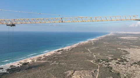 Aerial view of a tall crane in operation with the ocean in the background Stock Footage 294722662