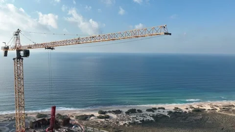 Aerial view of a tall crane in operation with the ocean in the background Stock Footage 294722670