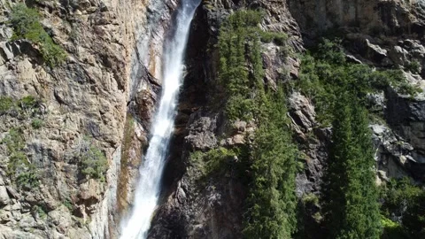 Aerial view of tall waterfall cascading between rocky cliffs and spruce trees Stock Footage 335093487
