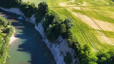 Aerial View of Tanaro River Flowing Past Cliffs and Wheat Fields 動画素材 336702631