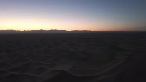 Aerial view of Tengger Desert at dusk with sand dunes and distant mountains Stock Footage 345370021