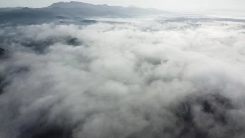 Aerial view of thick cloud cover blanket floating over mountain landscape at Stock Footage 343240838