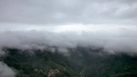 Aerial view of thick clouds drifting over lush green mountain valley landscape Stock Footage 342325536