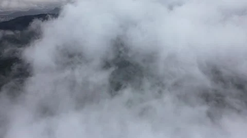 Aerial view of thick clouds drifting over a lush green mountain range Stock Footage 342325608