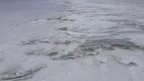 Aerial view of thick layer of salt deposits with footprints on them in coastal Stock Footage 195932368