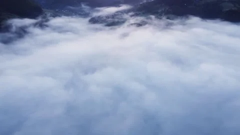 Aerial view of thick white clouds in a mountain forest valley above the trees 스톡 동영상 196986395